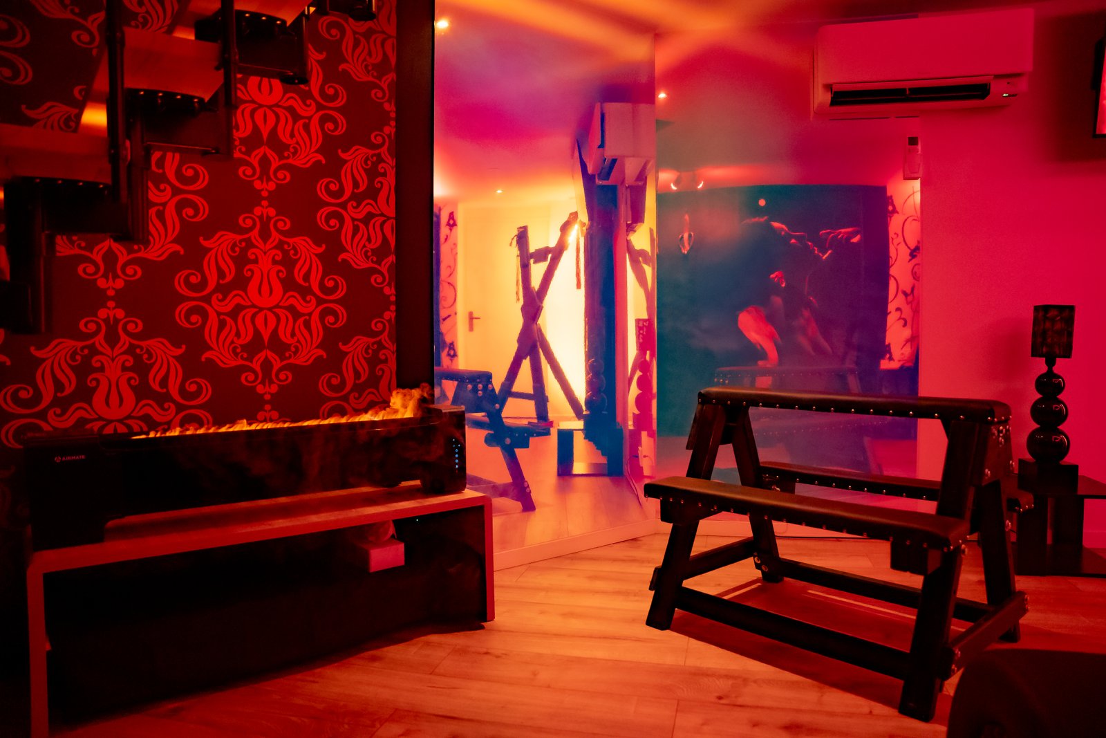 Sous-sol de la Suite Kinky — équipements BDSM et ambiance rouge velours